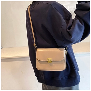 Detail view of a vintage beige crossbody bag with a gold metal clasp and leather strap