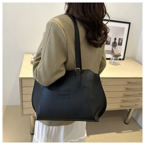Détail du grand sac cabas en cuir mat noir avec écusson logo sur la partie frontale