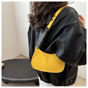 Detail of yellow quilted hobo bag with V-shaped texture and gold chain strap accent