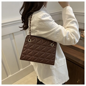 Detail of dark brown quilted crossbody bag with gold chain strap and diamond pattern