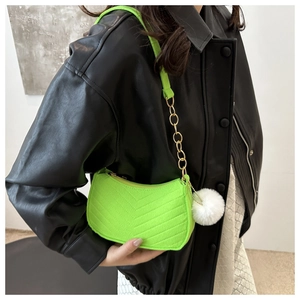 Detail of neon green V-quilted shoulder bag with gold chain and white fuzzy pompom charm
