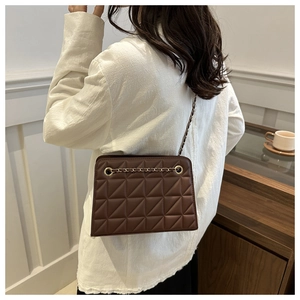 Detail of dark brown quilted crossbody bag with gold chain strap and diamond pattern