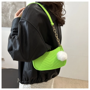 Close-up of neon green underarm bag with V-quilted texture, gold chain and plush charm