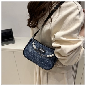 Detail of dark blue denim shoulder bag with pearl and metal flower chain decoration