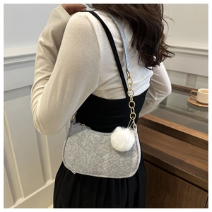 Detail of grey quilted wool underarm bag with gold chain strap and plush pompom charm