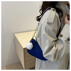 Blue suede underarm bag with V-shaped quilting, gold chain and plush ball charm detail