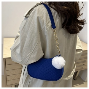 Blue V-quilted shoulder bag with fuzzy white pompom and gold chain strap detail