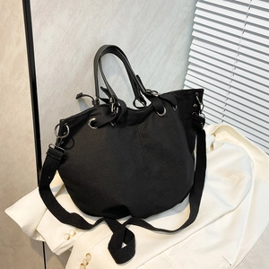 Large black canvas tote bag with leather handles and woven strap for daily commuting