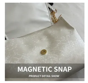 Detail showing the gold magnetic buckle and white snakeskin texture on a chic handbag