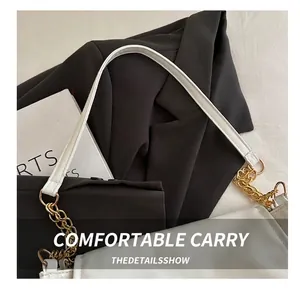 Detail of white PU leather shoulder bag with gold chain strap on black blazer background