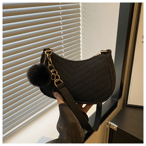 Close-up of black suede half-moon bag with V-quilted texture and gold chain strap