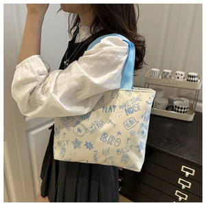 Canvas tote bag with blue graffiti bear and text worn by a model in a home setting