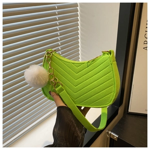 Detail of neon green crescent bag with V-shaped quilting, metal chain and fur pompom