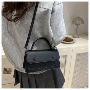Detailed view of a black crossbody bag with woven texture and a wide shoulder strap