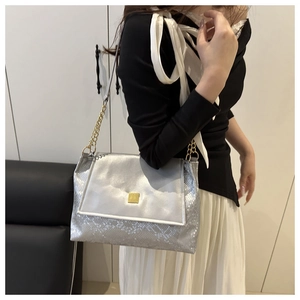Detailansicht der silbernen Schlangenmuster-Tasche mit goldener Kette und Verschluss