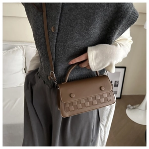 Close-up of brown faux leather shoulder bag with woven texture and top handle details