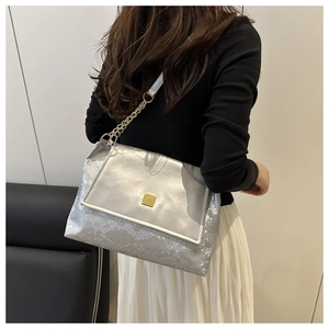 Detail of silver snake-pattern shoulder bag with gold square clasp on female model