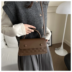 Brown rectangular plaid pattern handbag shown with model in a minimalist studio setting