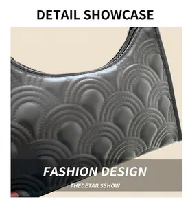Detail of black leather underarm bag featuring quilted scallop pattern and metal zipper