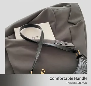 Detail of black crescent shoulder bag featuring elegant wave embossed faux leather and gold hardware