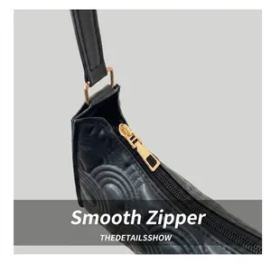 Detail of smooth gold zipper and textured circular leather pattern on black shoulder bag