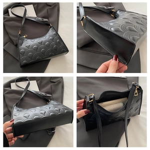 Detail view of black quilted baguette bag with gold hardware and interior storage space
