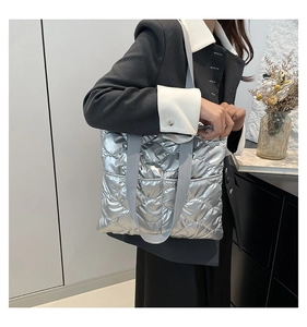 Close-up of silver quilted tote bag with metallic finish and grey woven handle
