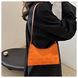 Detail of orange underarm bag with fan-shaped quilted texture and minimalist slim strap