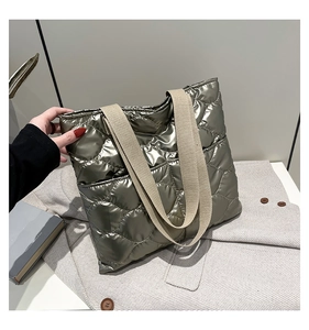 Detail of quilted metallic tote bag with beige woven straps and side pocket design