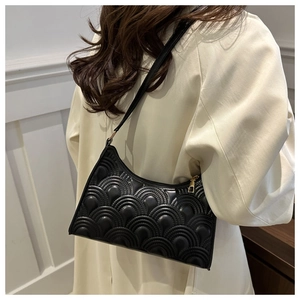 Detail of black quilted leather shoulder bag with gold zipper and shell pattern stitching