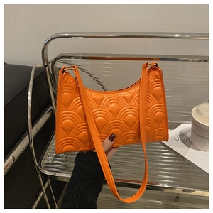 Close-up of vibrant orange underarm bag with unique embossed fish scale texture