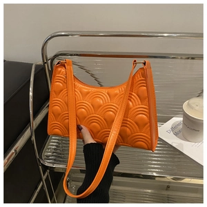 Detail of bright orange quilted baguette bag with fish scale pattern and zipper closure