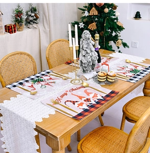 Christmas table set with four gnome placemats and a white lace runner on wooden table