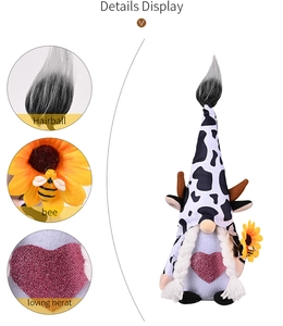 Detail view of gnome plush with cow pattern hat, pink glitter heart and sunflower bee