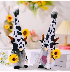 Detail view of cow print plush gnomes holding sunflowers in a warm home setting