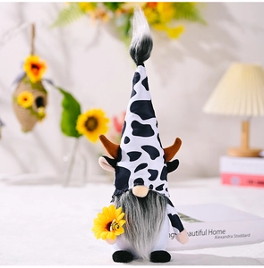 Detailed view of plush cow gnome holding a sunflower with bee accents in a cozy setting