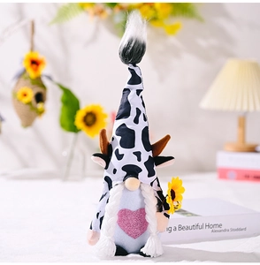 Close-up of a cow-patterned gnome plush toy holding a bright yellow sunflower decoration