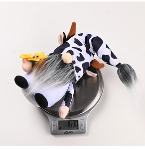 Gnome plush in cow print outfit with sunflower being weighed on a kitchen scale