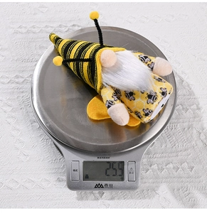 Dettaglio di uno gnomo ape di peluche su una bilancia digitale dal peso di 25,5 g