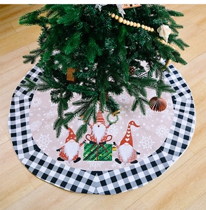 Detail of Christmas tree skirt with festive gnomes and buffalo plaid border on wood floor