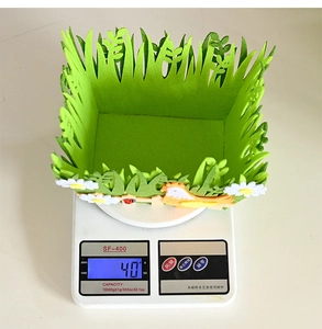 Detail showing a 40g lightweight green felt Easter basket with felt chick on a scale