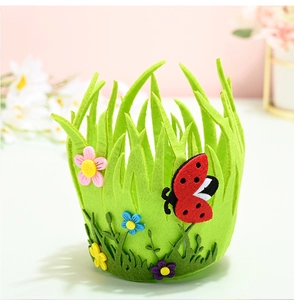 Detail of green felt Easter basket featuring felt flowers and ladybug on soft pink background