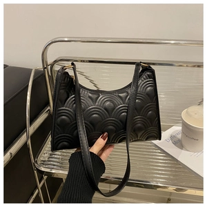 Detail of black underarm bag with unique wave-shaped quilted pattern and slim strap