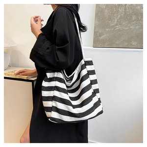 Close-up of a large black and white striped canvas tote bag worn on the shoulder
