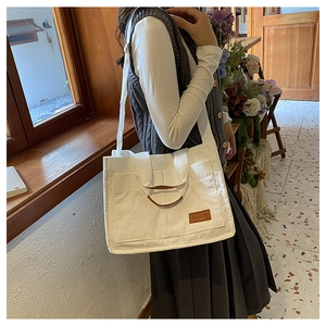 Close-up of white corduroy tote bag featuring leather brand tag and soft textured fabric