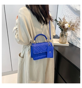 Detail of royal blue leather crossbody bag featuring embossed FASHION text and quilted texture
