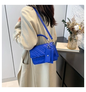 Detail of bright blue PU leather handbag with woven handle and fashion embossing on a model
