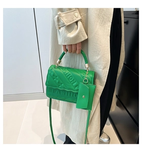Detail of bright green PU leather bag with FASHION embossing and braided handle