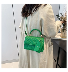 Detail of green quilted handbag with woven handle and small detachable coin purse