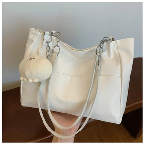 Détail d'un sac cabas blanc avec chaîne métallique élégante et peluche de poulpe